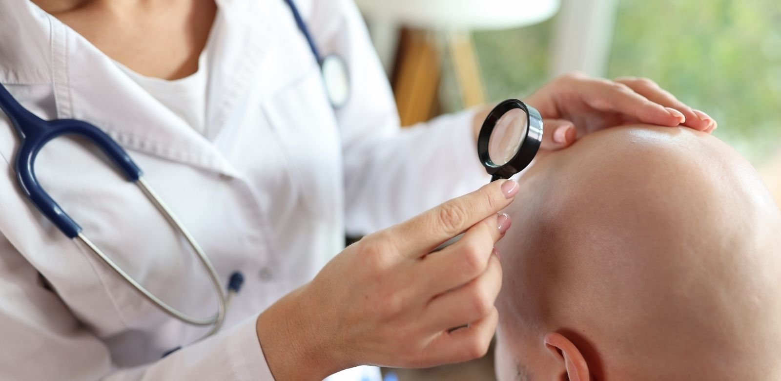 Doctor examining a patient's scalp with a magnifying glass at a hair transplant clinic in Antalya